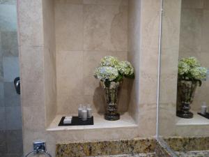 克雷塔罗Hotel Amberes的浴室设有两瓶花和蜡烛