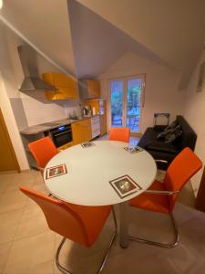 格拉达茨Apartments Grozdana的厨房配有白色的桌子和橙色的椅子