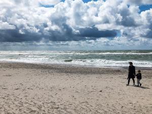 法贾德嘉德8 person holiday home in Ulfborg的海滩上行走的女人和孩子