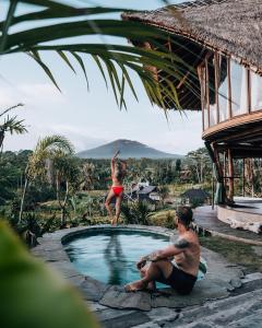 希德门Veluvana Bali的站在度假胜地游泳池边缘的女人