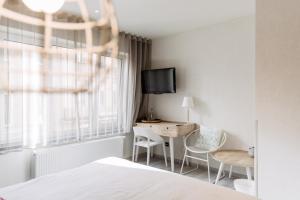 布兰肯贝赫赫利俄斯C-酒店的一间卧室配有一张床、一张书桌和一台电视。