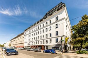 维也纳维也纳JR城市公寓的一条街道上一座白色的大建筑,有停放的汽车