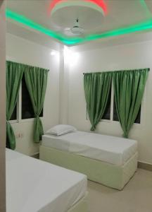 菩提伽耶RAJHAT MARANAO House的绿窗帘间内的两张床