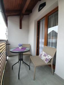 兹拉蒂博尔Zlatibor Hills LARA的阳台配有一张紫色桌子和两把椅子