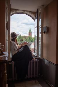 库尔迪加Roberta Hercberga Apartamenti的坐在窗户旁读书的女人