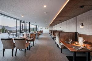 马兰扎雪绒花酒店的餐厅设有木桌、椅子和窗户。
