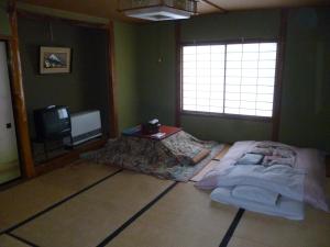 山之内町乌托市旅馆的一间卧室配有一张床和一台电视。