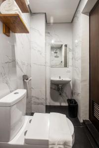 马尼拉Airo Hotel Manila的白色的浴室设有卫生间和水槽。