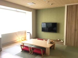 京都Kyoto Central Inn的客厅配有桌子和墙上的电视