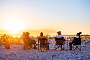 NgomaChobe River Campsite的一群坐在椅子上观看日落的人