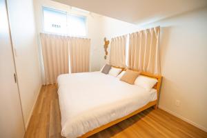 那霸Hotel Tomas Asahibashi Station的一间卧室配有一张带白色床单的床和一扇窗户。