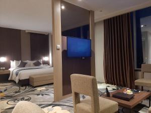 哥伦打洛省ASTON Gorontalo Hotel & Villas的配有一张床和一台平面电视的酒店客房