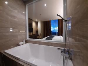 哥伦打洛省ASTON Gorontalo Hotel & Villas的带浴缸和镜子的浴室