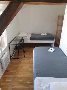 DienvilleChaleureuse maison au coeur d'un joli village的小房间设有两张床和一张玻璃桌