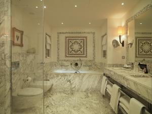 佛罗伦萨萨沃伊罗科·福尔蒂酒店的浴室配有2个盥洗盆、浴缸和淋浴。