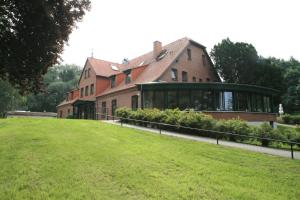 柯莱恩内美洛黑德霍夫海景酒店的一座大型砖屋,前面有一片绿色草坪