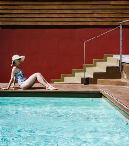 皮索涅Lake Hotel La Pieve的坐在游泳池旁的戴帽子的女人