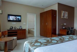 库马西Frederick's Lodge的卧室配有一张床,墙上配有电视。