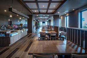 神栖市Hotel Route-Inn Kamisu的餐厅设有木桌、椅子和窗户。