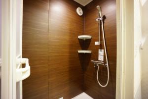 东京RoNa Hotel的带淋浴的浴室和木墙