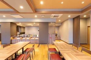 樱井市Hotel Route-Inn Sakurai Ekimae的餐厅设有木桌、椅子和柜台