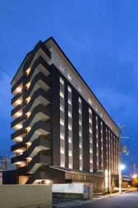 樱井市Hotel Route-Inn Sakurai Ekimae的一座黑色的大建筑,灯火通明