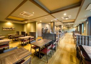 香取市Hotel Route-Inn Katori Sawara Ekimae的一间带木桌和椅子的餐厅和一间自助餐厅