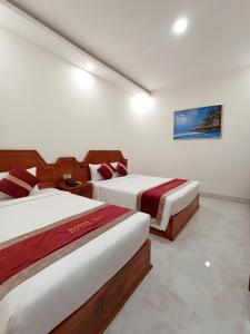 Bạc LiêuRoyal Hotel 2的酒店客房设有两张床,墙上挂有绘画作品