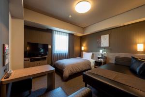 鹿沼Hotel Route-Inn Kanuma Inter的酒店客房,配有床和沙发
