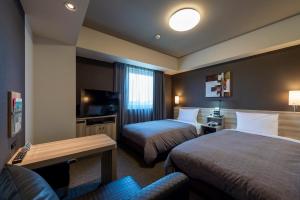 鹿沼Hotel Route-Inn Kanuma Inter的酒店客房,设有两张床和一张沙发