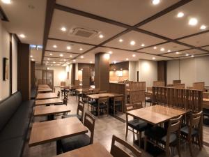 增田Hotel Route-Inn Masuda的一间空餐厅,配有木桌和椅子