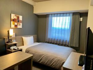 EchizenHotel Route-Inn Takefu Inter的酒店客房设有床和窗户。