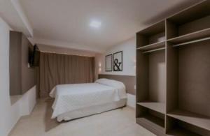 若昂佩索阿Manaíra Apart Hotel的一间卧室配有床和一些书架
