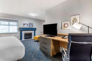 阿伯茨福德Clarion Hotel & Conference Centre的一间卧室配有一张床和一张书桌及电视