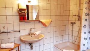 杜伊斯堡豪斯舍特恩酒店的白色瓷砖浴室设有水槽和浴缸