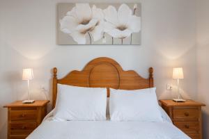 塞维利亚Apartamento cerca del Alcázar con garaje privado的一间卧室配有一张带白色枕头的床和两盏灯。