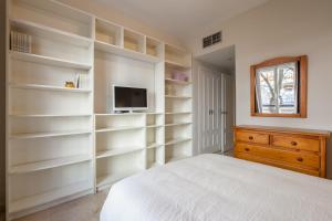 塞维利亚Apartamento cerca del Alcázar con garaje privado的卧室配有白色的架子、床和电视。