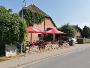 奥特里德维茨Gasthof-Ferienwohnungen-Kliesow´s Reuse的大楼前的餐厅,带红伞和鲜花