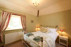 肯德尔Autumn Cottage的一间卧室设有一张床、一个窗户和一个吊灯。