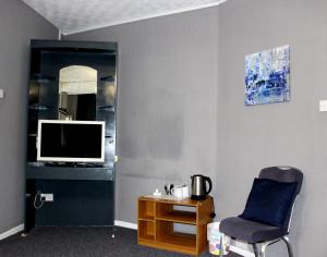 布莱克浦游乐海滩亨森酒店的一间带椅子、电视和桌子的房间