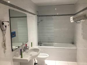 卢尔德Hôtel Angelic的白色的浴室设有浴缸、水槽和卫生间。