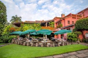 库埃纳瓦卡卡拉斯马纳尼塔斯酒店的粉红色建筑前的庭院,配有桌子和遮阳伞
