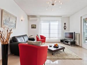 科麦里奥Belvilla by OYO Varese Tre的客厅配有黑色沙发和红色椅子