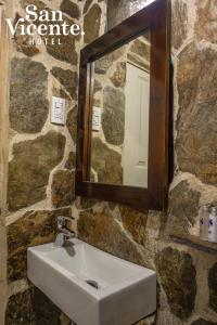 圣罗莎德卡瓦尔Hotel Termales San Vicente的浴室设有水槽和石墙上的镜子