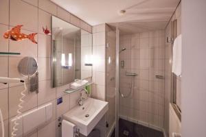 埃森迈克希米利安酒店的一间带水槽、淋浴和镜子的浴室