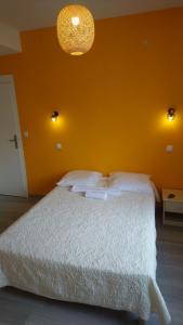 莱斯帕尔梅多克CAFE DE PARIS的一间卧室配有一张白色的床和橙色的墙壁