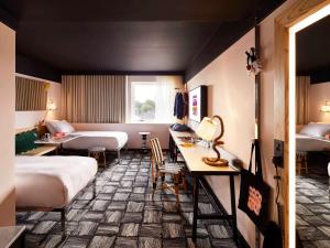 伦敦Mama Shelter London - Shoreditch的酒店客房带两张床和一张桌子以及椅子。