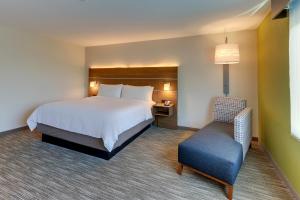 罗阿诺Holiday Inn Express & Suites - Roanoke – Civic Center的配有一张床和一把椅子的酒店客房