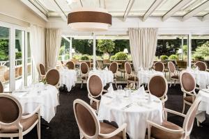 梅拉诺米拉奈洛夫经典酒店的餐厅设有白色的桌椅和窗户。