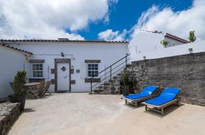 诺德什蒂Casa Vista da Marquesa的白色房屋前的天井配有2把蓝色躺椅